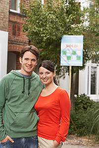 年轻夫妇在新家门前用售卖牌子的肖像闲暇房地产女士财产男人房子男性男士搬迁幸福图片