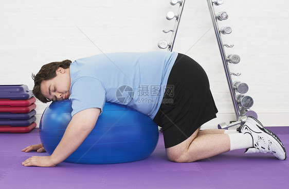 一个超重男人睡在健康俱乐部运动舞会上的侧面景象图片