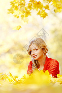 女人躺在秋叶上快乐女孩喜悦乐趣橙子微笑红色幸福森林公园图片