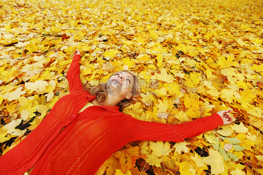 女人躺在秋叶上橙子女孩金发红色女性微笑乐趣森林快乐金子图片