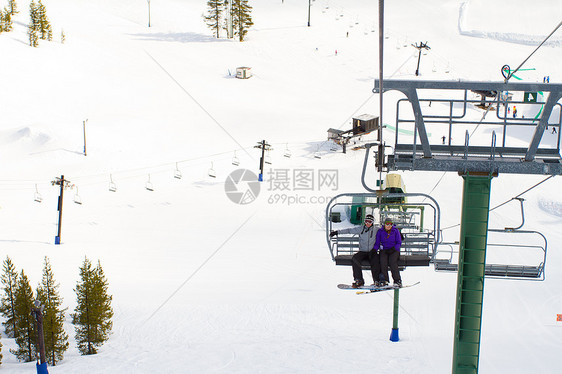 搭乘滑雪电梯的一对夫妇白色旅行升降椅运动极限单板滑雪板缆车男人滑雪者图片