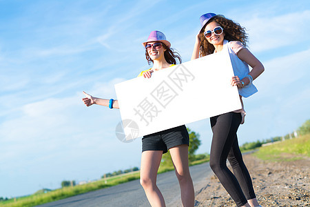 两名年轻女性站在空白的横幅上站着假期航程女士远足者季节纸板自由女孩冒险成人图片