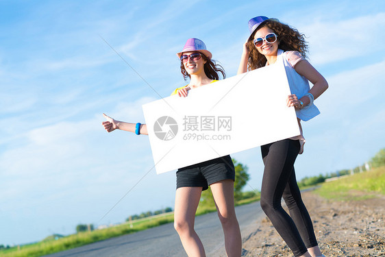 两名年轻女性站在空白的横幅上站着假期航程女士远足者季节纸板自由女孩冒险成人图片