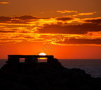 在Punta Nati 橙色日落观众天空蓝色假期地标晴天海滩支撑海岸太阳图片