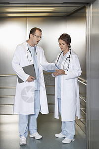 一名男女医生在医院电梯中讨论病历表的全长医师人数图片