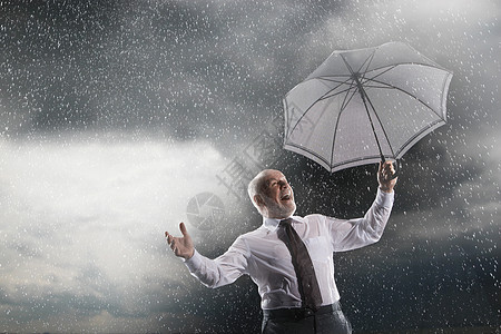 中年商务人士的低角度视野 雨伞在风暴中大笑图片