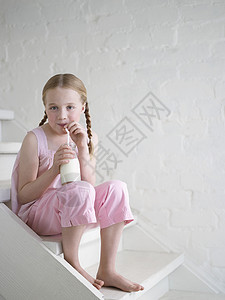 一个赤脚女孩在楼梯上喝杯牛奶的肖像图片