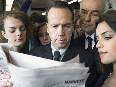 站在火车上阅读报纸的通讯员肩并肩站立图片