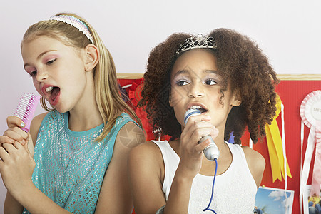 多族裔少女在睡梦派对上用刷子作为麦克风唱歌的多族裔女孩朋友们卡拉ok嘴巴活力睡眠青春期娱乐童年孩子闲暇图片