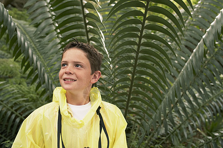 穿雨衣的小男孩站在野外旅行时 大幼兽面前图片
