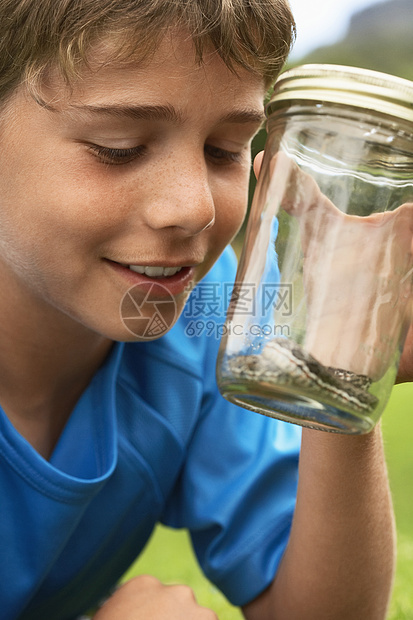 快乐的年轻男孩在户外看蛇罐中图片