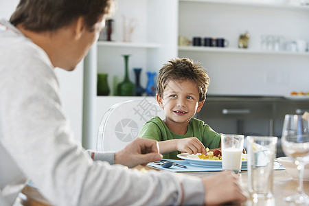 与父亲在餐桌吃饭的年轻男孩图片