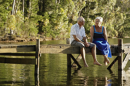坐在湖边码头的一对快乐的老年情侣图片