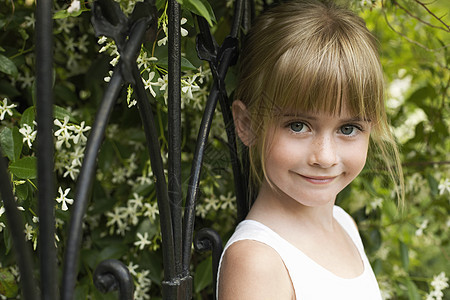 坐在篱笆上快乐的年轻女孩的肖像图片
