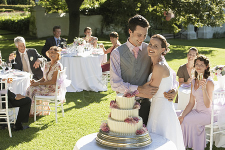 在花园的成人新娘和新郎中 与持有葡萄酒杯的婚礼嘉宾图片