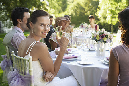 新娘坐在婚礼桌前 带着酒杯微笑图片