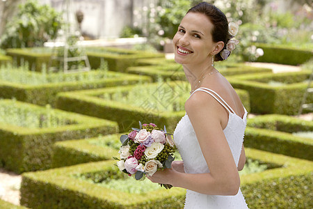 美丽的年轻新娘的肖像 在正规花园里盛满玫瑰花束图片