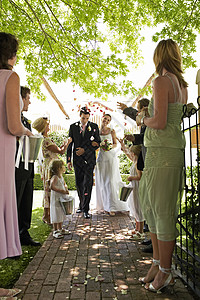 新娘和新郎走在路上 人们向空气中投掷花瓣享受燕尾服混合范围风俗人生盘子海关花束小路图片
