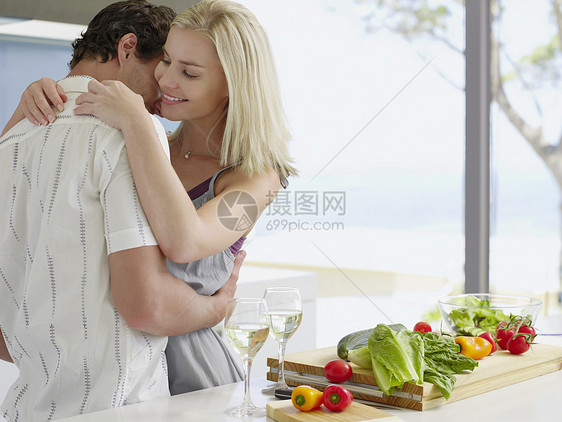 在厨房柜台收着新鲜蔬菜的浪漫年轻夫妇 食堂柜台图片