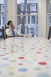 在餐桌使用手机的正规青年商务人士;在餐桌上使用手机图片