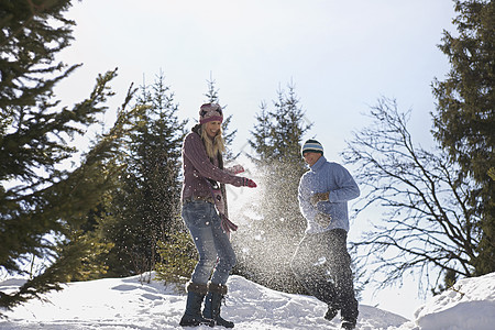 一对夫妇在山上的雪中玩耍的低角度视图女性男性天空针织品男人俏皮成人斗争衣服假期图片