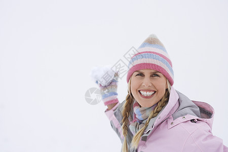 一个快乐的年轻女子在冬天扔雪球的肖像帽子成人闲暇女士衣服针织品乐趣恶作剧假期微笑图片