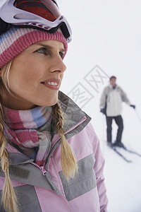 妇女站在滑雪斜坡上 男子站在背景滑雪上休闲滑雪镜针织帽成人服装活动沉思女性一个人中年人图片