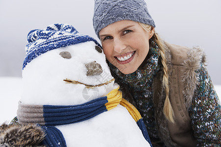 在雪覆盖的山丘上 由雪人为一位快乐的年轻女子图片
