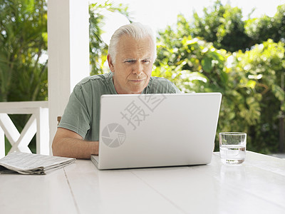 在verandah桌使用笔记本电脑的成熟男子阳台闲暇专注桌子男人技术树木白色门廊成人图片