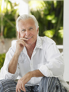 坐在Verandah上 一个笑着的成熟男人的肖像头发快乐退休衬衫阳台成人白色门廊闲暇喜悦图片
