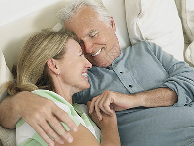 一个快乐的中年夫妇 拥抱在床上的近身景色图片