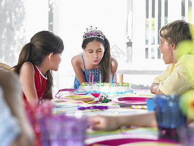 女孩在户外派对上吹出生日蜡烛童年桌子孩子们庆典前院男生生日闲暇团体后院图片