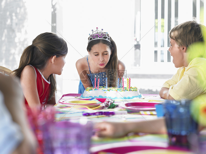 女孩在户外派对上吹出生日蜡烛童年桌子孩子们庆典前院男生生日闲暇团体后院图片
