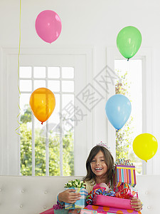 一个年轻女孩的肖像 带着生日礼物微笑孩子房间沙发青春期派对享受皇冠幸福房子气球图片