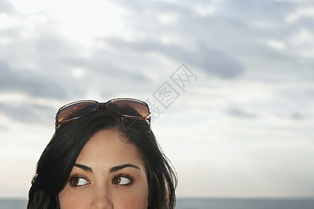 紧紧关紧闭少女的太阳镜 在头顶对着阴云的天空图片
