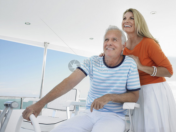 中年微笑的中年夫妇驾驶游艇图片