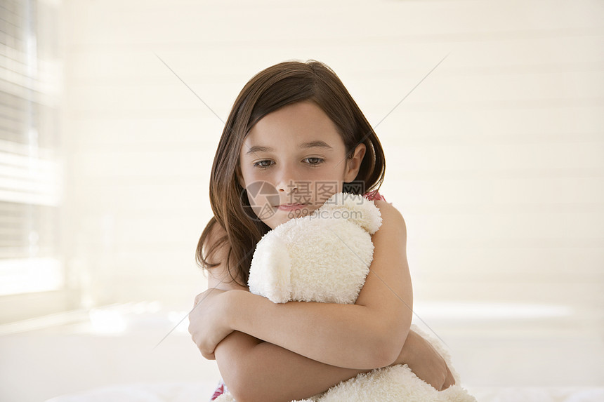 带着泰迪熊抱在床上的悲哀少女图片