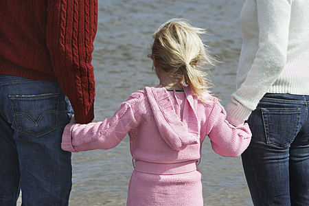 女儿与父母在海滩上牵手的近视图片