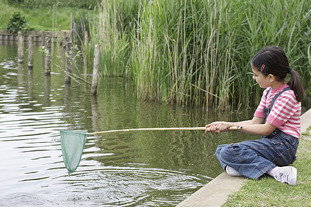 整个快乐的年轻女孩在河边网钓鱼图片