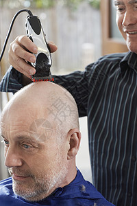 理发师剃着老人头的胡子 在发廊用电剪裁缝图片
