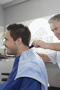 男人从理发店理发师剪头发的侧面视图图片