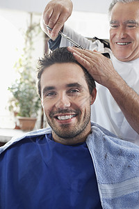 在理发店理发师剪头发时 快乐男人的肖像图片
