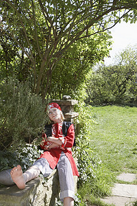 一个身穿海盗服装的男孩坐在花园里 手交叉着手臂坐着图片