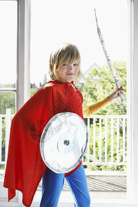 佩戴玩具盾和剑的超级英雄服装中 一个自信的小男孩的肖像图片