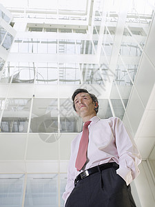 一个自信的商务人士在办公楼阁楼露天站立的低角度视角图片