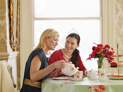 两位坐在饭桌上喝茶的年轻女青年女性金发女郎窗户杯子公寓聊天桌子古董沟通房间图片