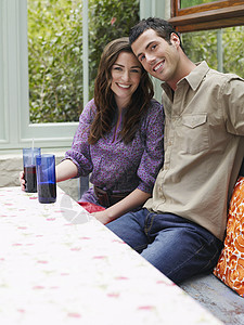 坐在Verandah桌子上的一对微笑的年轻夫妇的肖像闲暇女士阳台玻璃夫妻喜悦朋友们团结成人社交图片