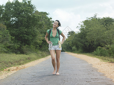 一名身穿短裤 赤脚在农村公路上行走的年轻女子全长肖像图片