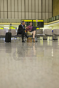 在机场大厅使用膝上型电脑的商务人士和妇女图片