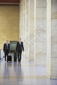 两名笑着的商务人士在机场前厅拉行李 满身双面微笑的商务人士图片